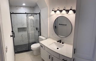 Finished bathroom with glass shower and round mirror