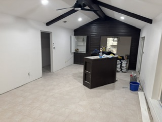 Vaulted living space with tile flooring and dark cabinetry island