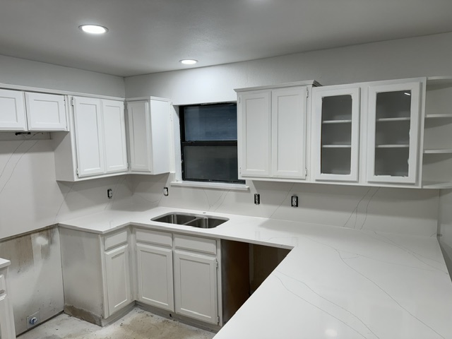 Finished kitchen with white cabinets and quartz counters